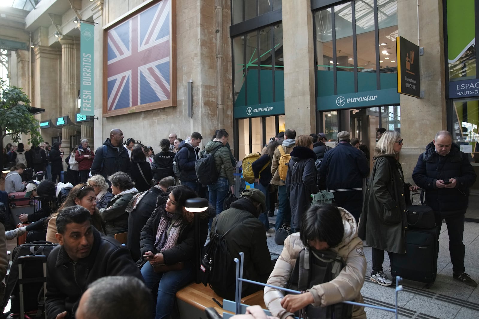 Travelers wait as Eurostar trains to London and all trains heading to northern France have been brought to a halt following the discovery of an unexploded bomb dating back to World War II near the tracks, Friday, March 7, 2025 at the Gare du Nord station in Paris. (AP Photo/Christophe Ena)