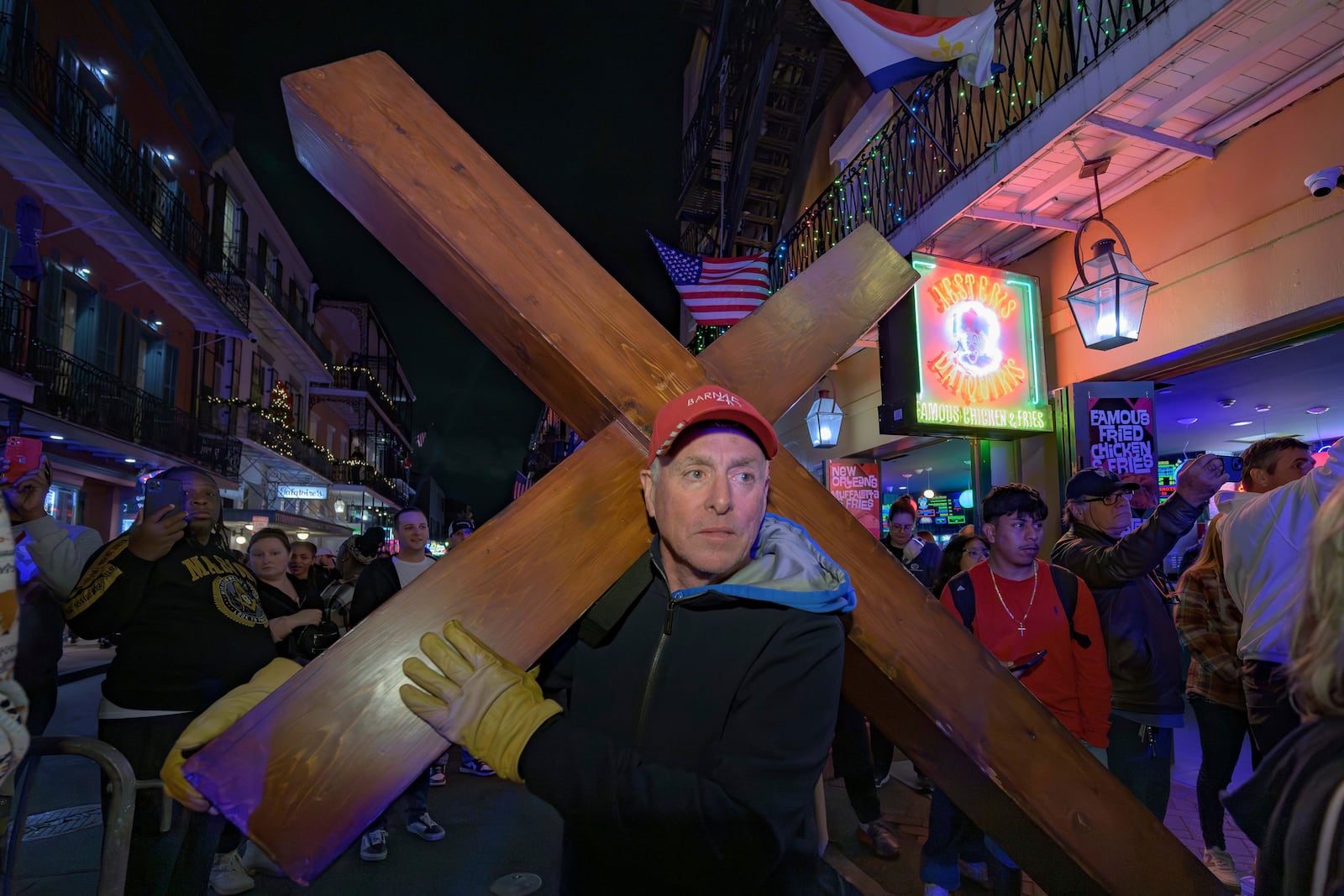 Dan Beazley, of Northville, Mich., walks with a cross in front of a parade on Bourbon Street in New Orleans, Saturday, Jan. 4, 2025, as they memorialize the victims of the New Year's Day deadly truck attack and shooting. (AP Photo/Matthew Hinton)