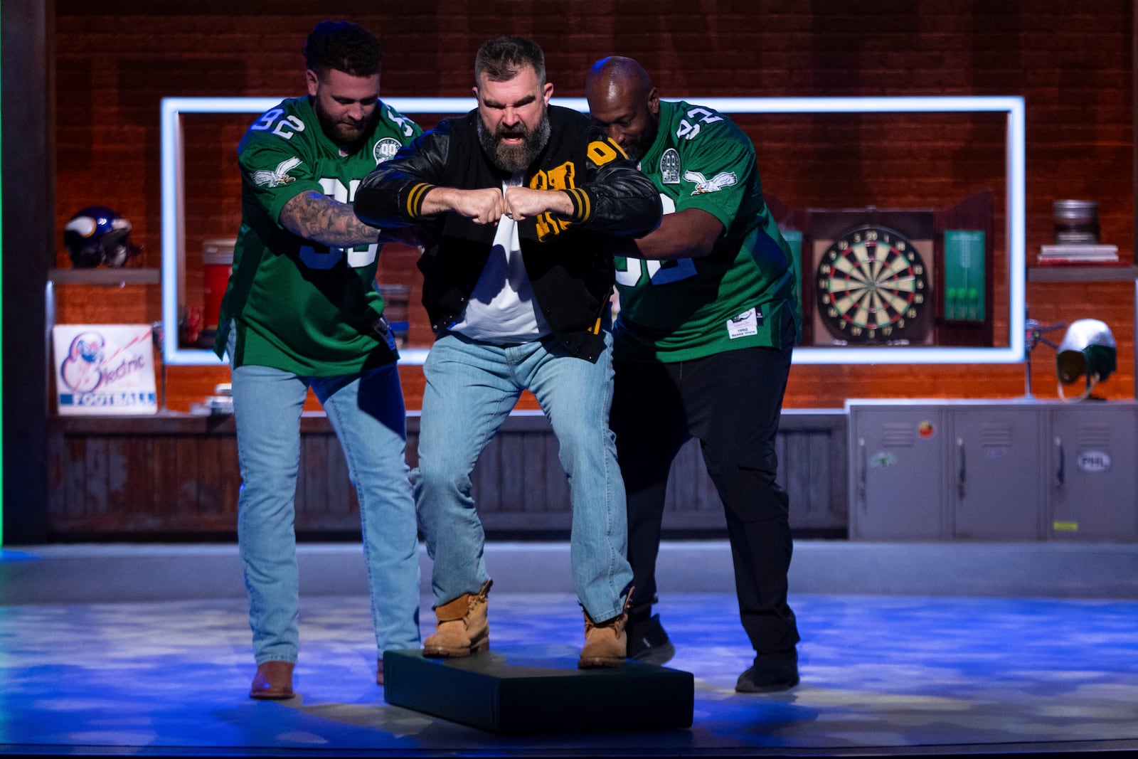 Former NFL player and ESPN analyst Jason Kelce, center, gets pushed out like an old electronic football player during the taping of "They Call It Late Night with Jason Kelce", Friday, Jan. 3, 2025, in Philadelphia. (AP Photo/Chris Szagola)