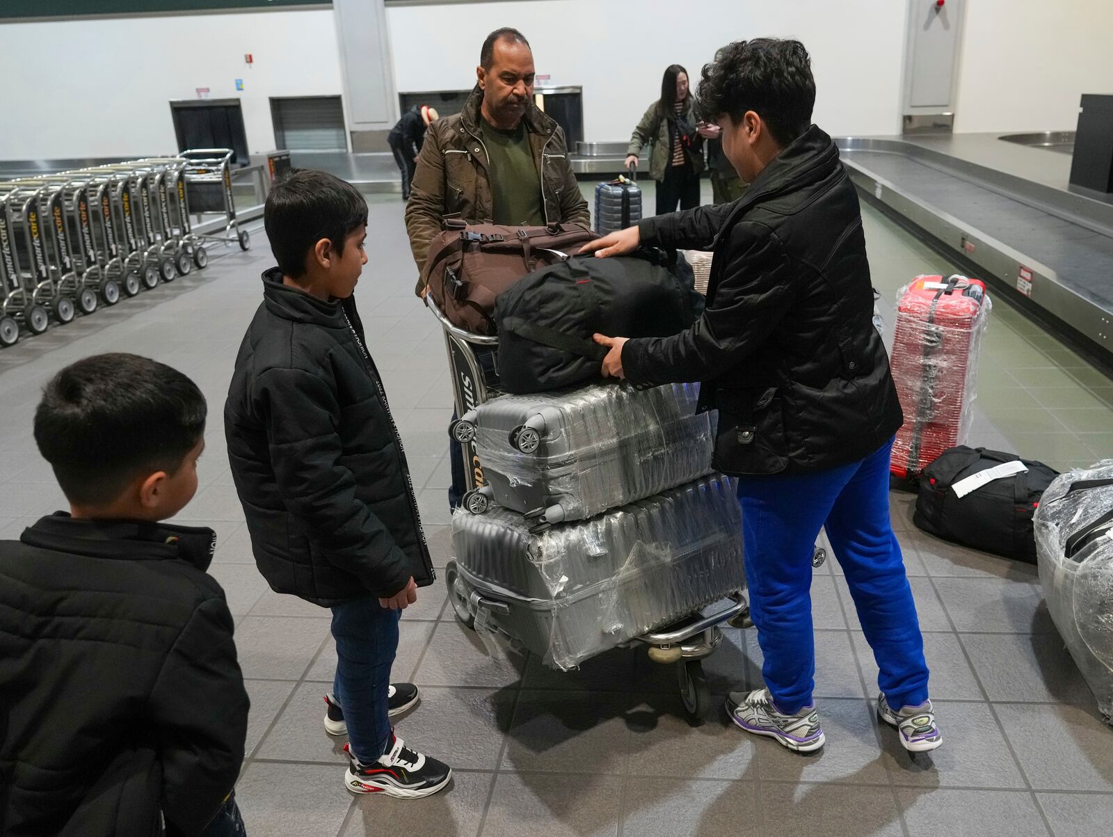 Mohammad Saboor Osmani, center, and his son's Mohammad Shabir Osmani, left, Mohammad Samir Osmani, second from left and Mohammad Seyar Osmanni, right, load their luggage on a cart after their arrival at the Sacramento International Airport in Sacramento, Calif., Tuesday, March 11, 2025. (AP Photo/Rich Pedroncelli).