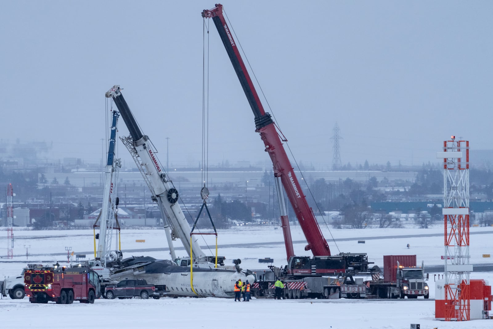 Cranes are positioned to remove the wreckage of Delta Flight 4819 from the runway at Toronto Pearson International Airport, in Mississauga, Ontario, on Wednesday, Feb. 19, 2025. (Arlyn McAdorey/The Canadian Press via AP)