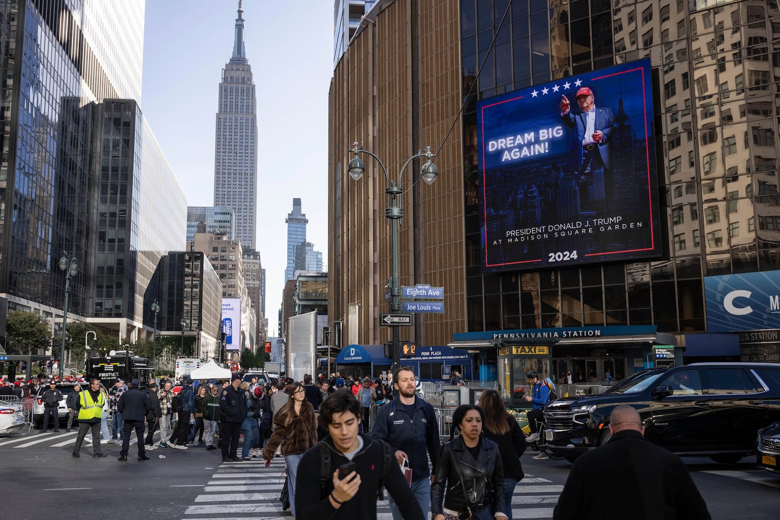 People walk past video boards displaying information about the campaign rally for Republican presidential nominee former President Donald Trump outside Madison Square Garden, Sunday, Oct. 27, 2024, in New York. (AP Photo/Yuki Iwamura)