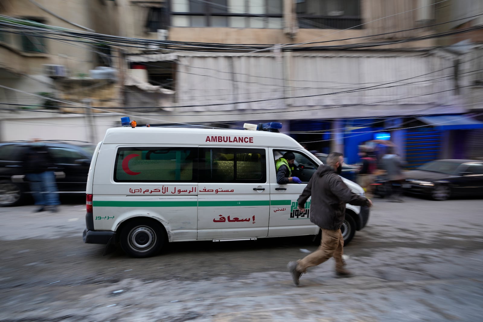 A man runs next to an ambulance arriving at the site of an Israeli airstrike that targeted a building in Beirut, Lebanon, Tuesday, Nov. 26, 2024. (AP Photo/Hassan Ammar)