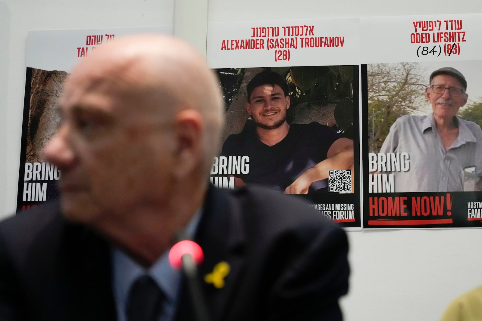 Louis Har, a former Israeli hostage, is backdropped by photos of hostage still held by Hamas during a press conference in Rome, Thursday, Nov. 14, 2024. (AP Photo/Alessandra Tarantino)