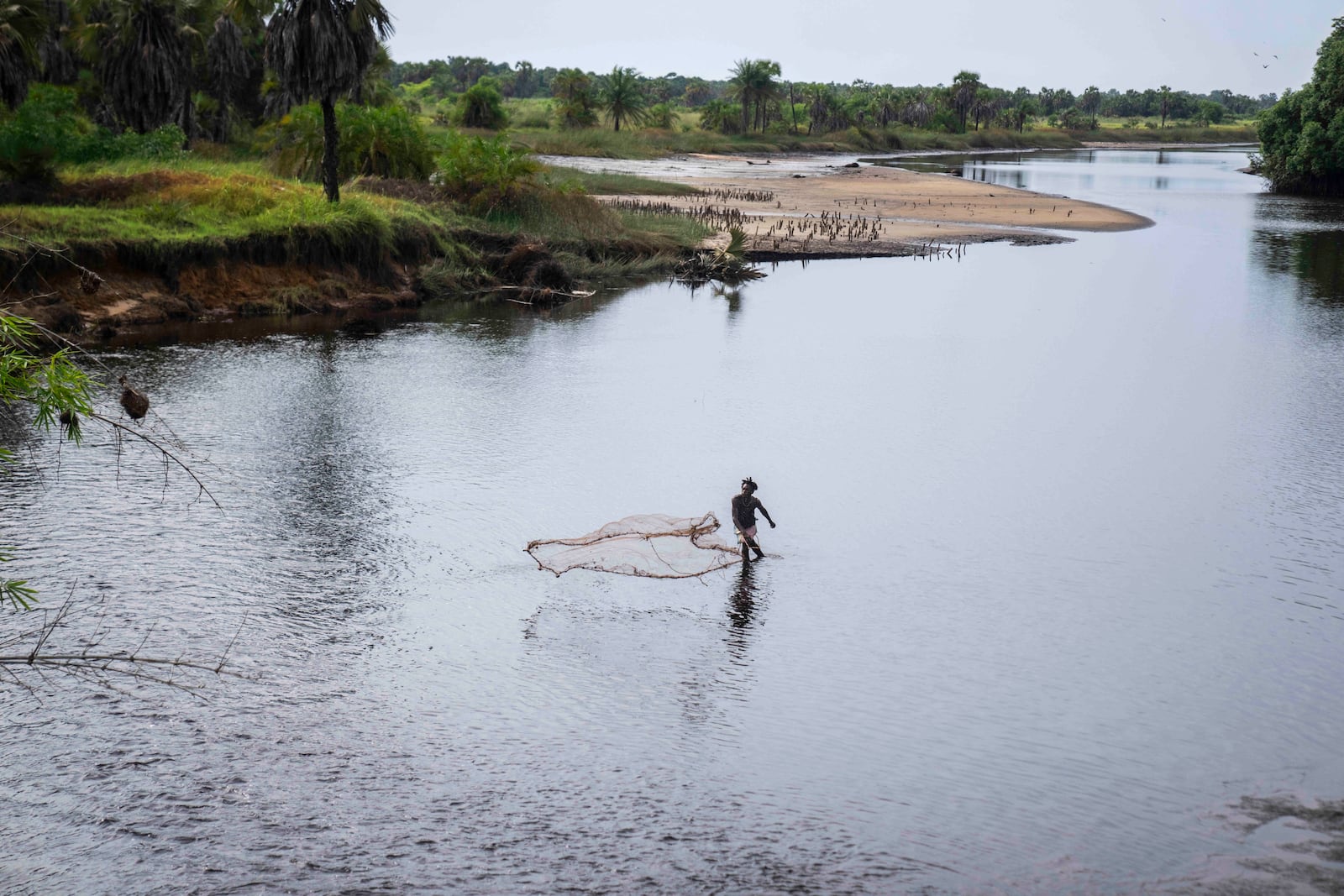 FILE - A fisherman casts his net in a lake polluted by oil on the outskirts of Moanda, western Democratic Republic of Congo, Dec. 23, 2023. (AP Photo/Mosa'ab Elshamy, File)