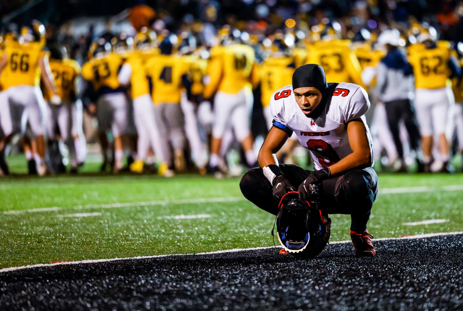 Lakota West Malik Hartford reflects on their Division I Regional final football playoff game loss as Moeller celebrates in the background Friday, Nov. 19, 2021 at Dwire Field in Mason. Moeller won 21-17. NICK GRAHAM / STAFF