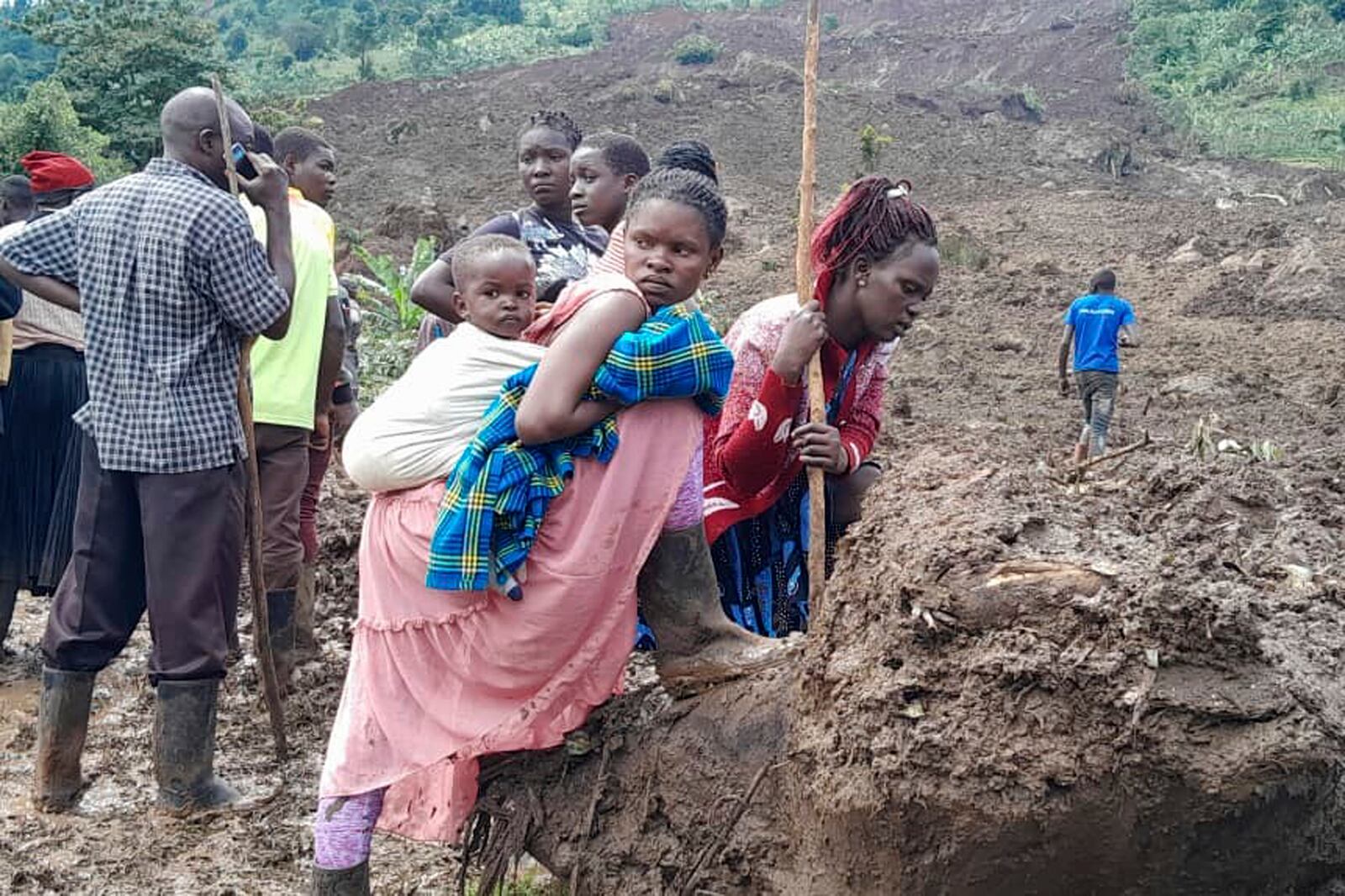 Rescue workers and people search for bodies after a landslide following heavy rains that buried 40 homes in the mountainous district of Bulambuli, eastern Uganda, Thursday, Nov. 28. 2024. (AP Photo/Jean Watala)