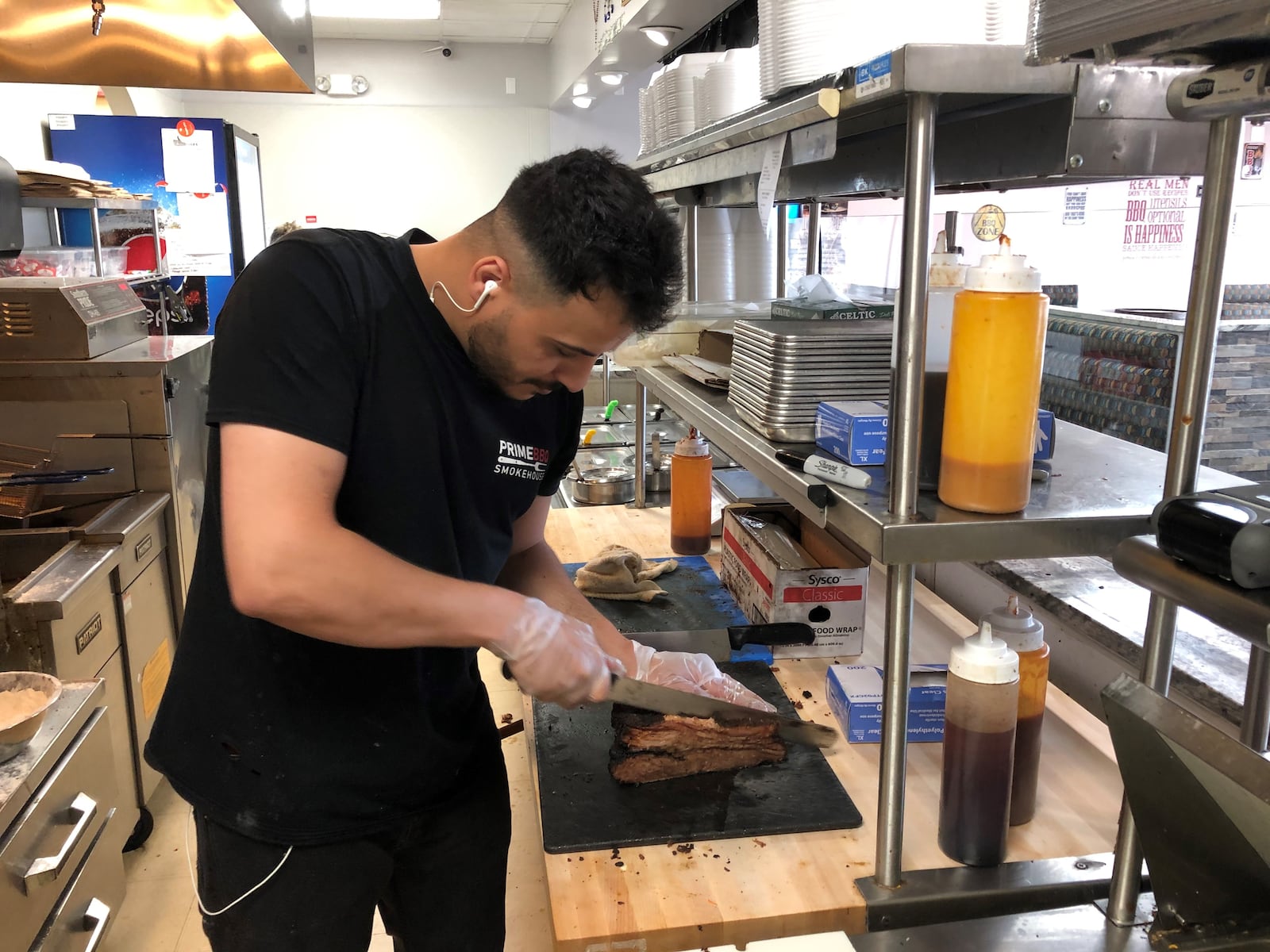 Prince Ahmed, a cook at Prime BBQ Smokehouse in Monroe, cuts brisket. The restaurant opened during the coronavirus pandemic and has been successful, one of the partners said. RICK McCRABB/STAFF