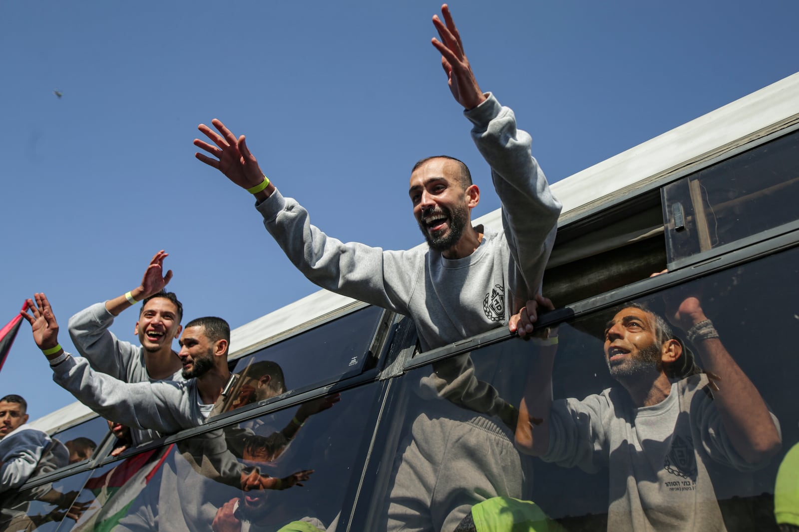 Freed Palestinian prisoners wave from a bus as they arrive in the Gaza Strip after being released from an Israeli prison following a ceasefire agreement between Hamas and Israel in Khan Younis, Saturday, Feb. 1, 2025. (AP Photo/Jehad Alshrafi)