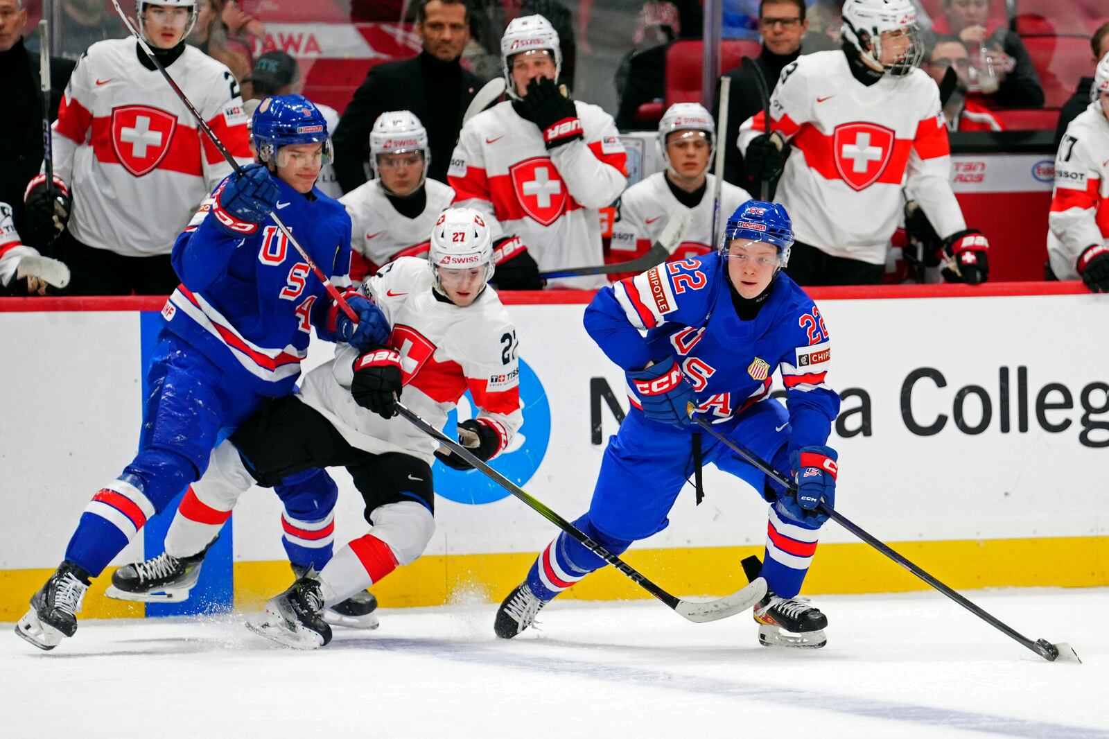 USA forward Brandon Svoboda, left, checks Switzerland forward Simon Meier (27) as USA forward Max Plante (22) skates with the puck during the third period of a quarterfinal match at the IIHF World Junior Hockey Championship in Ottawa, Ontario Thursday, Jan. 2, 2025. (Sean Kilpatrick/The Canadian Press via AP)