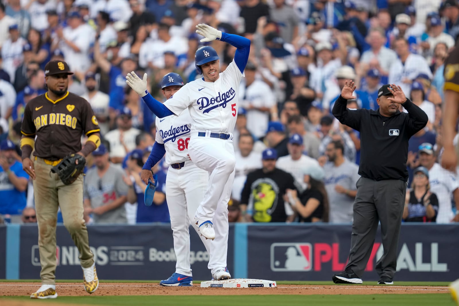 Los Angeles Dodgers' Freddie Freeman (5) reacts after a single as he stands next to San Diego Padres first baseman Luis Arraez during the first inning in Game 5 of a baseball NL Division Series Friday, Oct. 11, 2024, in Los Angeles. (AP Photo/Ashley Landis)