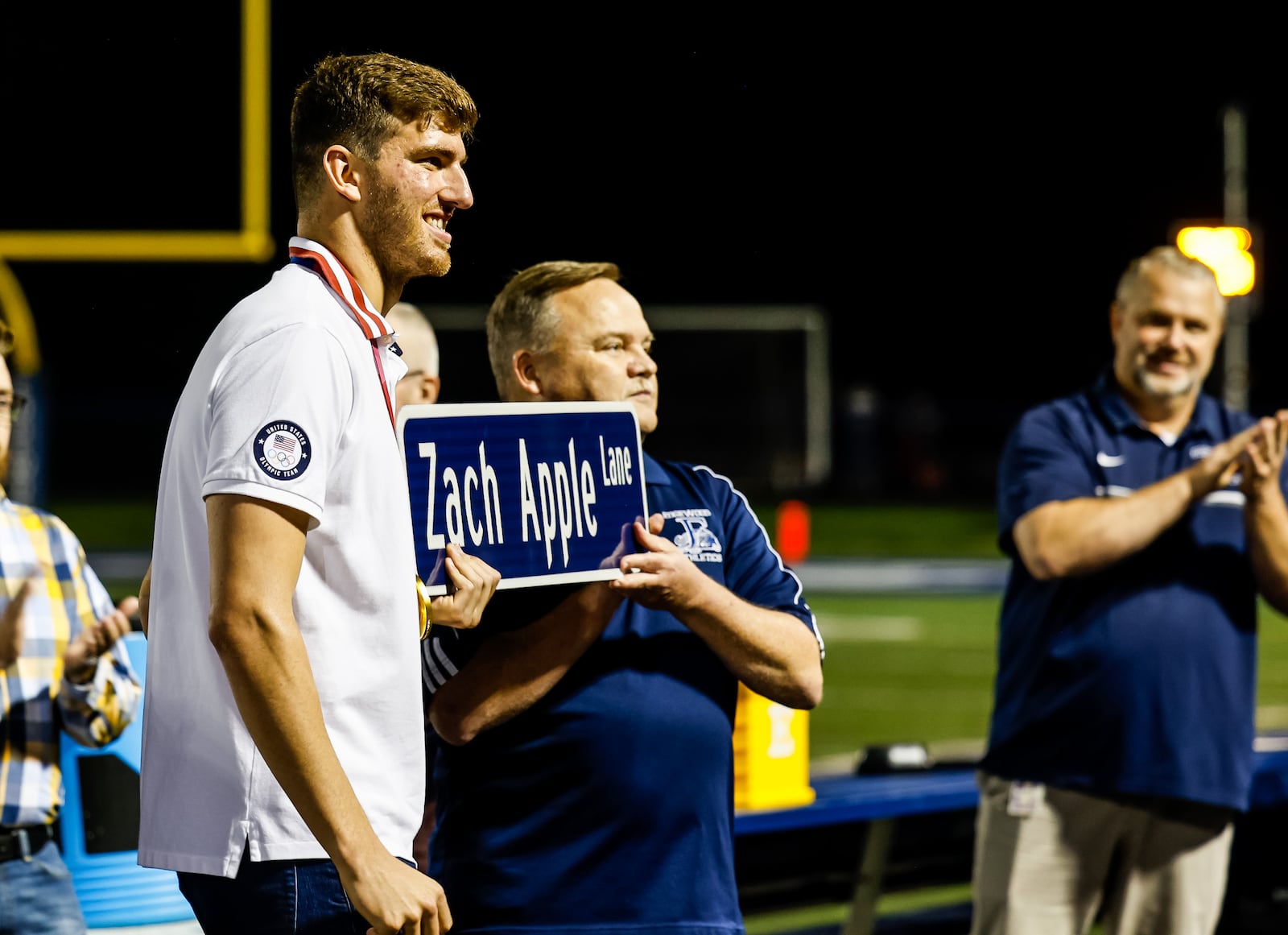 Trenton native and 2015 Edgewood High School graduate Zach Apple was honored at halftime of the Edgewood football game Friday, Oct. 8, 2021 at Edgewood's Kumler Field. Apple won two gold medals for swimming in the 2020 Tokyo Olympics held this year. Edgewood school board president Jim Wirtley presented Apple with a sign that will be installed near the high school naming a section of road Zach Apple Way. NICK GRAHAM / STAFF