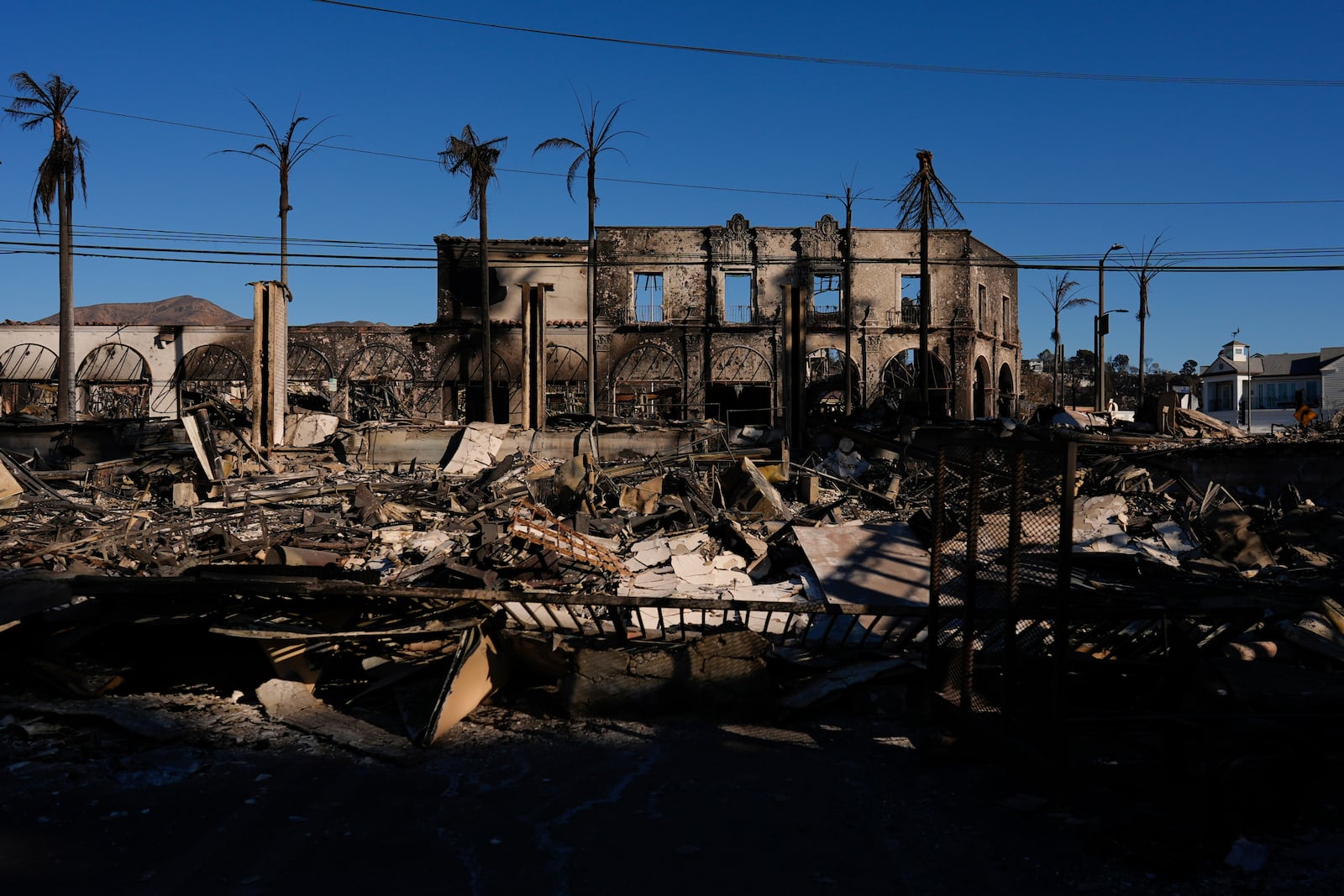 Burned businesses are left behind by the Palisades Fire in the Pacific Palisades neighborhood of Los Angeles, Tuesday, Jan. 14, 2025. (AP Photo/Carolyn Kaster)