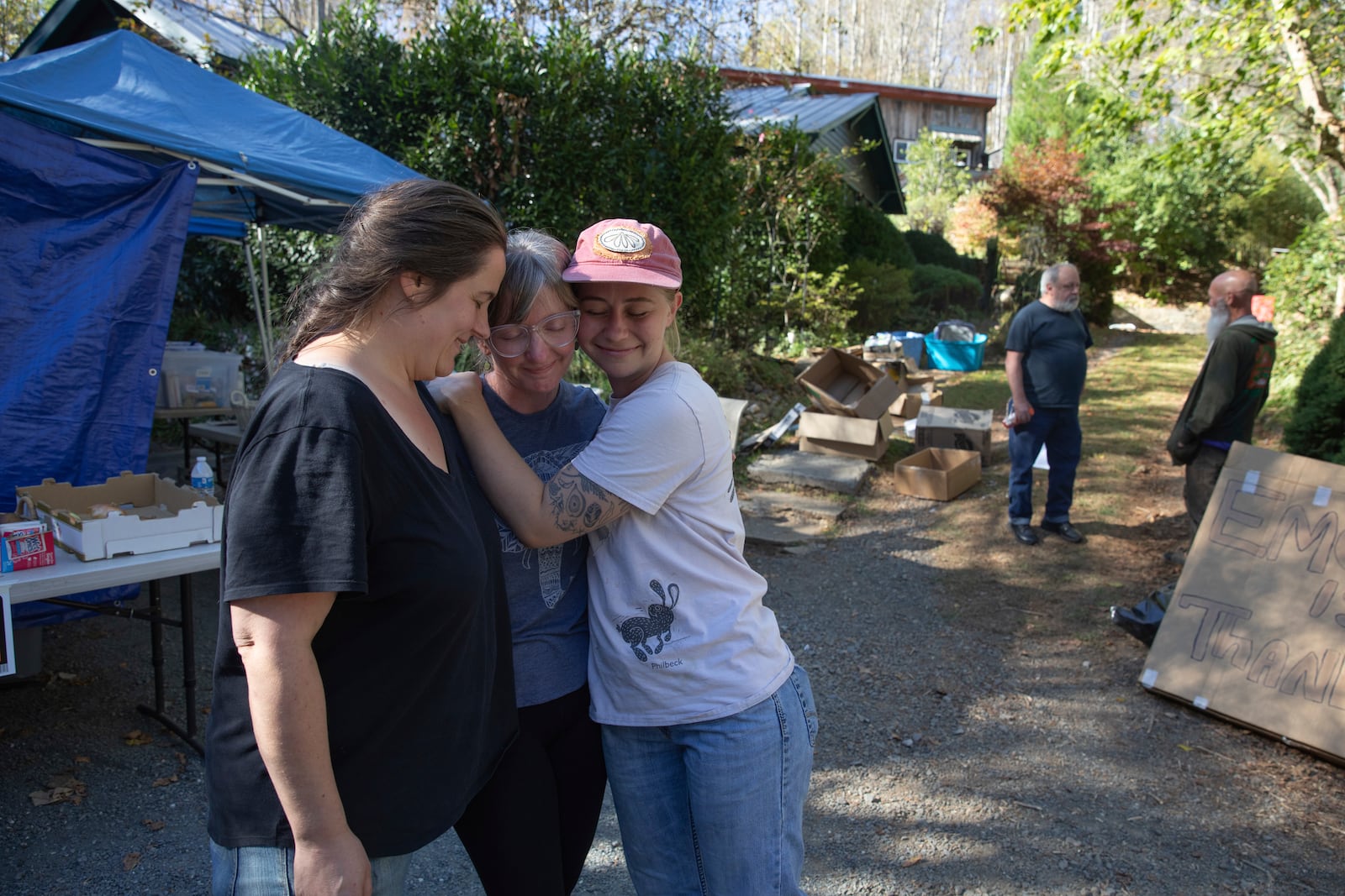 Rose Hardesty, left, Julie Wiggins, center, and Em Trentham, right, stand outside a makeshift distribution hub they manage for neighbors in Bakersville, N.C. on Oct. 9, 2024. (AP Photo/Gabriela Aoun Angueria)