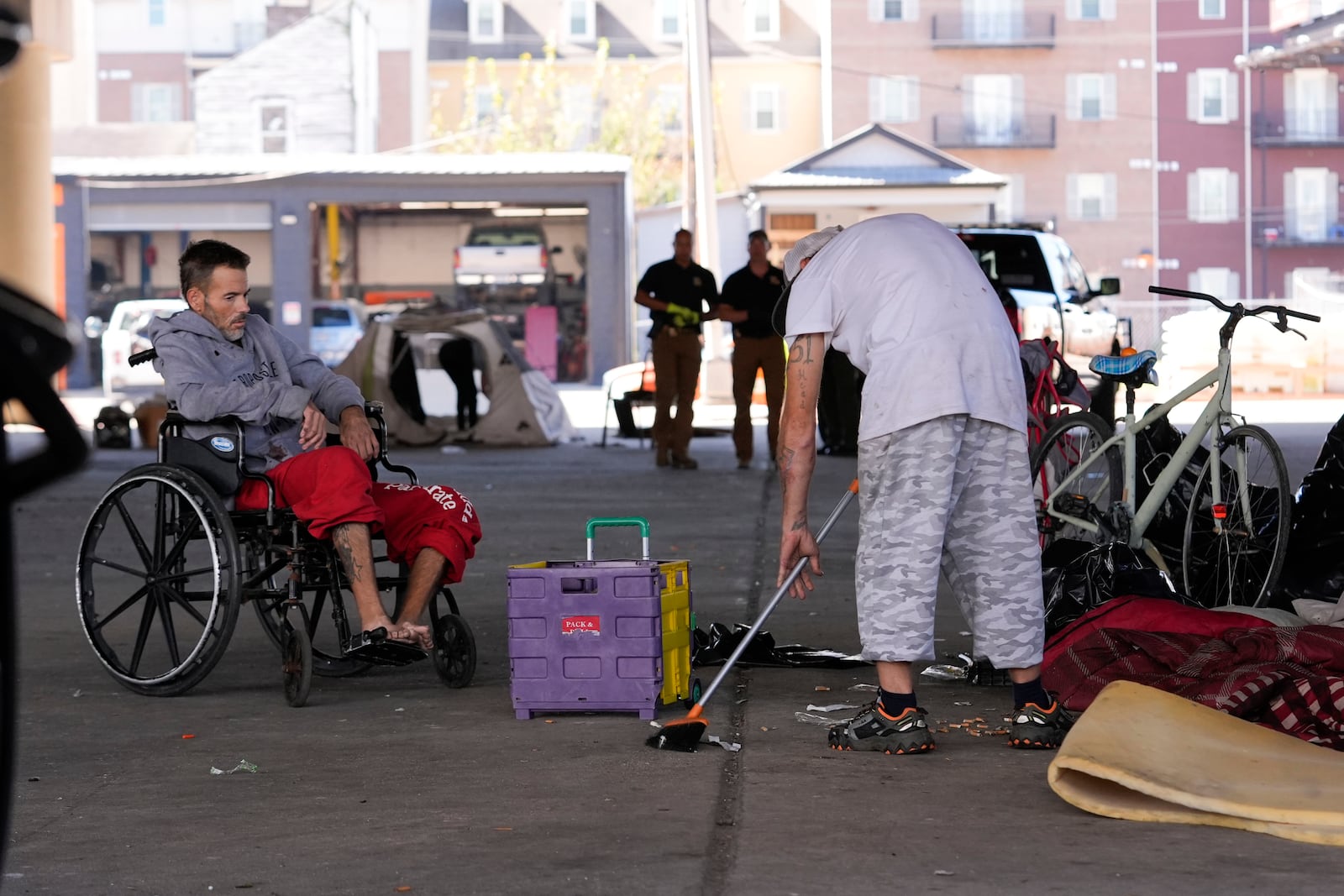 A man living in a homeless encampment sweeps up after Louisiana State police gave instructions for them to move to a different pre-designated location as they perform a sweep in advance of a Taylor Swift concert in New Orleans, Wednesday, Oct. 23, 2024. (AP Photo/Gerald Herbert)