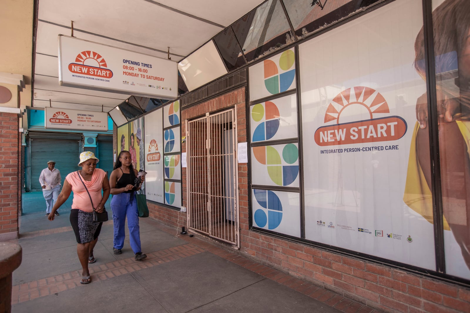 Women walk past a closed New Start centre that used to provide free HIV testing as well as anti retroviral treatment in Chitungwiza, Zimbabwe, Friday, Feb. 7, 2025. (AP Photo/Aaron Ufumeli)