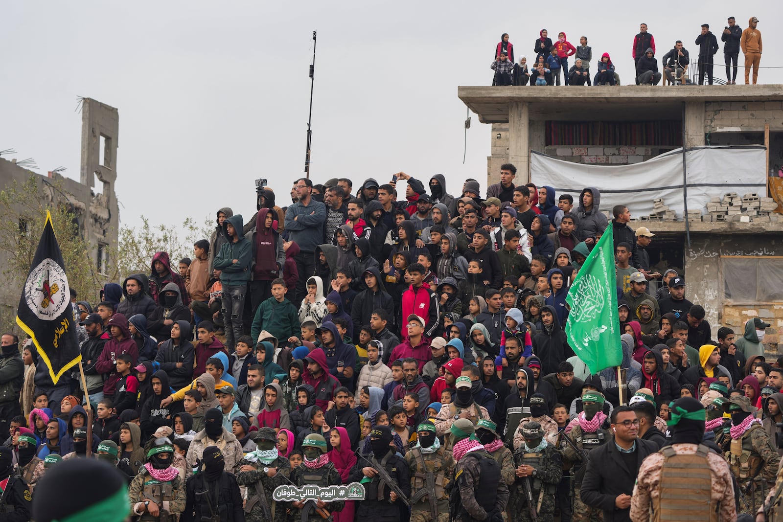 Palestinians gather as Hamas fighters deploy ahead of handing over the bodies of four Israeli hostages, including a mother and her two children, who had long been feared dead, to the Red Cross in Khan Younis, southern Gaza Strip, Thursday, Feb. 20, 2025. (AP Photo/Abdel Kareem Hana)