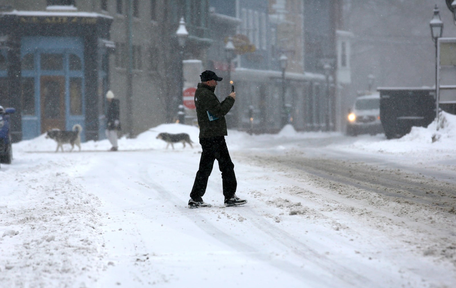 People walk in snowy streets during a storm in Portsmouth, N.H., Thursday, Feb. 6, 2025. (AP Photo/Caleb Jones)