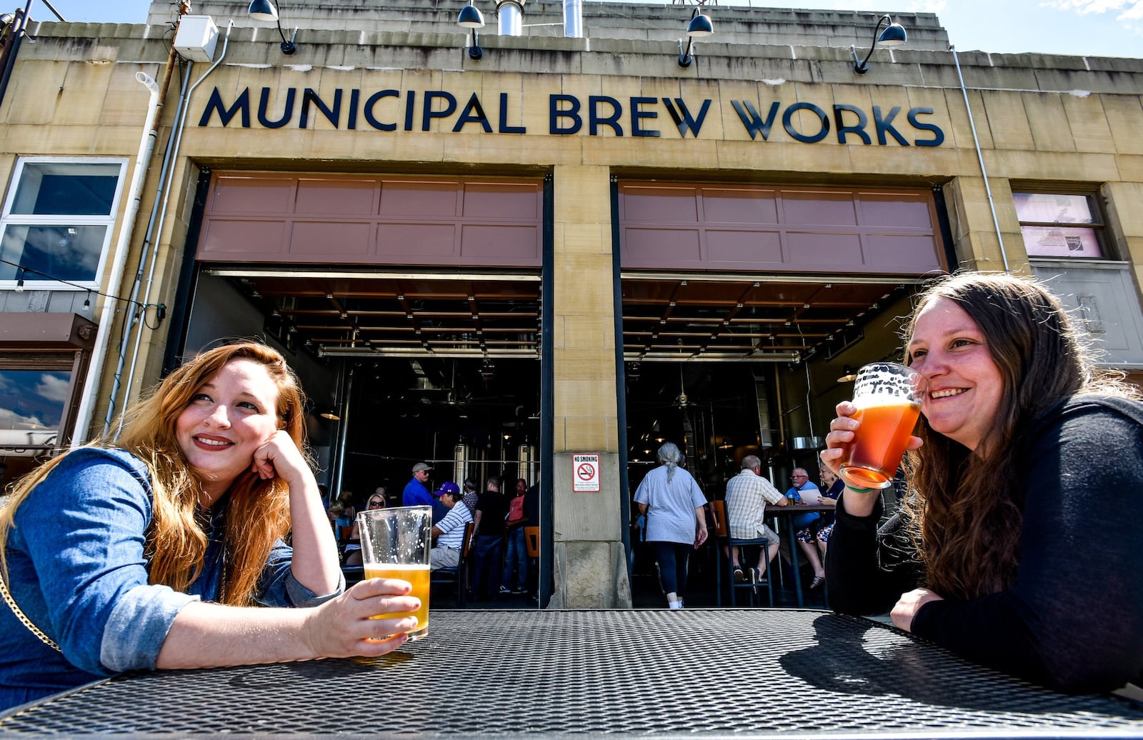 Kyla Oglesbee, left, and Sarah Shepherd try out the beers during the grand opening last June of Municipal Brew Works in Hamilton. The brewery has several special events planned this weekend to celebrate its first year in business. NICK GRAHAM/STAFF