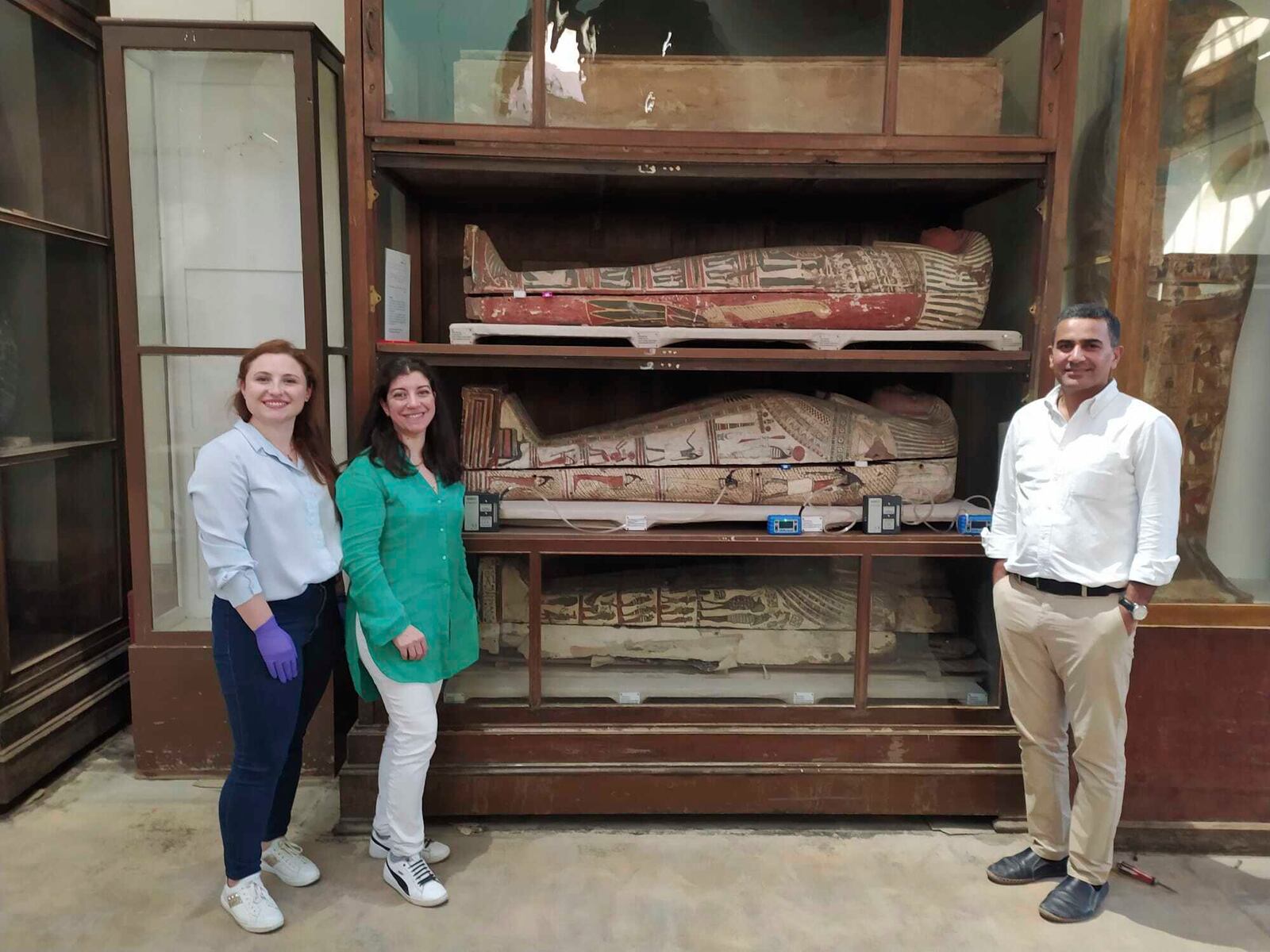 In this undated photo provided by Ahmed Abdellah, from left, Emma Paolin, PhD student at University of Ljubljana, Dr. Cecilia Bembibre, lecturer at the University College London, prof. Dr. Abdelrazek Elnaggar, part of the research team at the Egyptian museum in Cairo pose for a photo with a selection of the mummified bodies. (Ahmed Abdellah via AP)