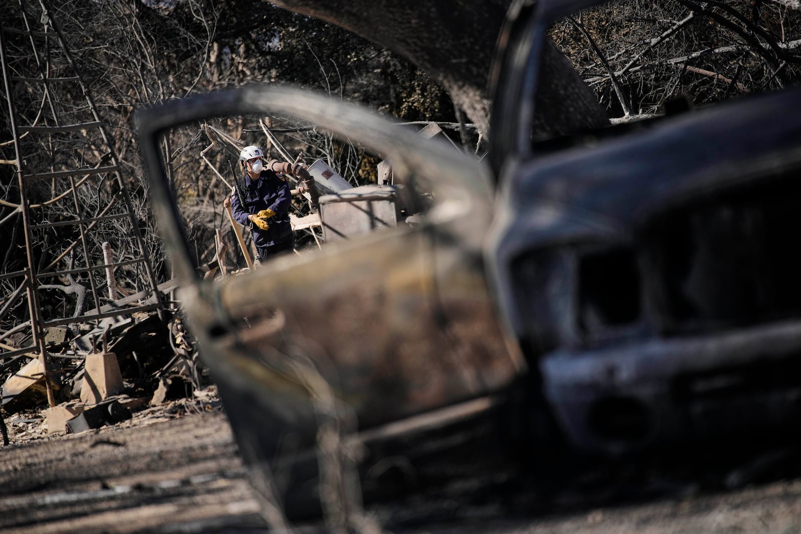 A search and rescue worker sifts through the wreckage of a home destroyed by the Eaton Fire, Tuesday, Jan. 14, 2025, in Altadena, Calif. (AP Photo/John Locher)