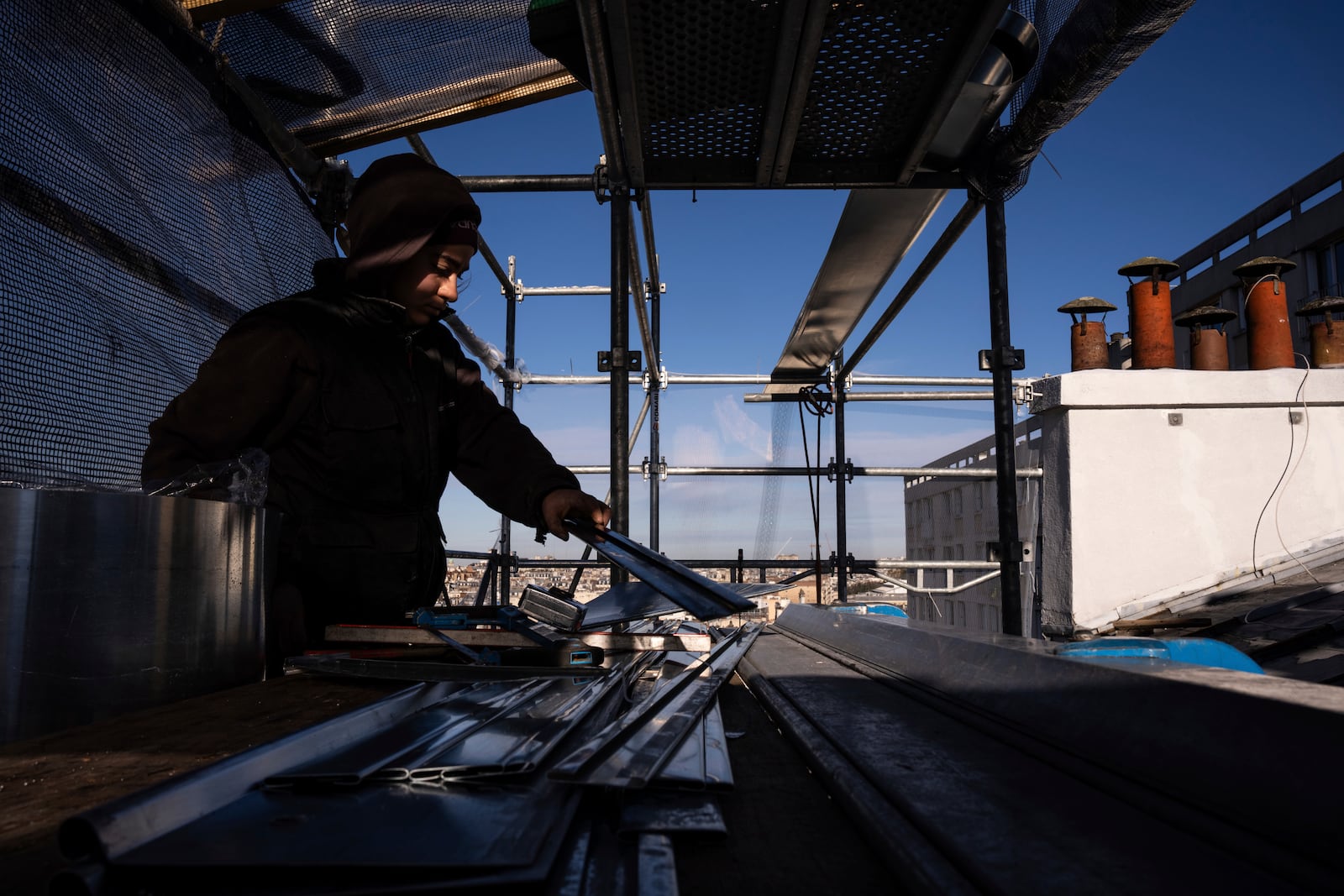 Fantine Dekens, 21, cuts zinc sheets on the roof of a building in Paris, Wednesday, Nov. 20, 2024. (AP Photo/Louise Delmotte)