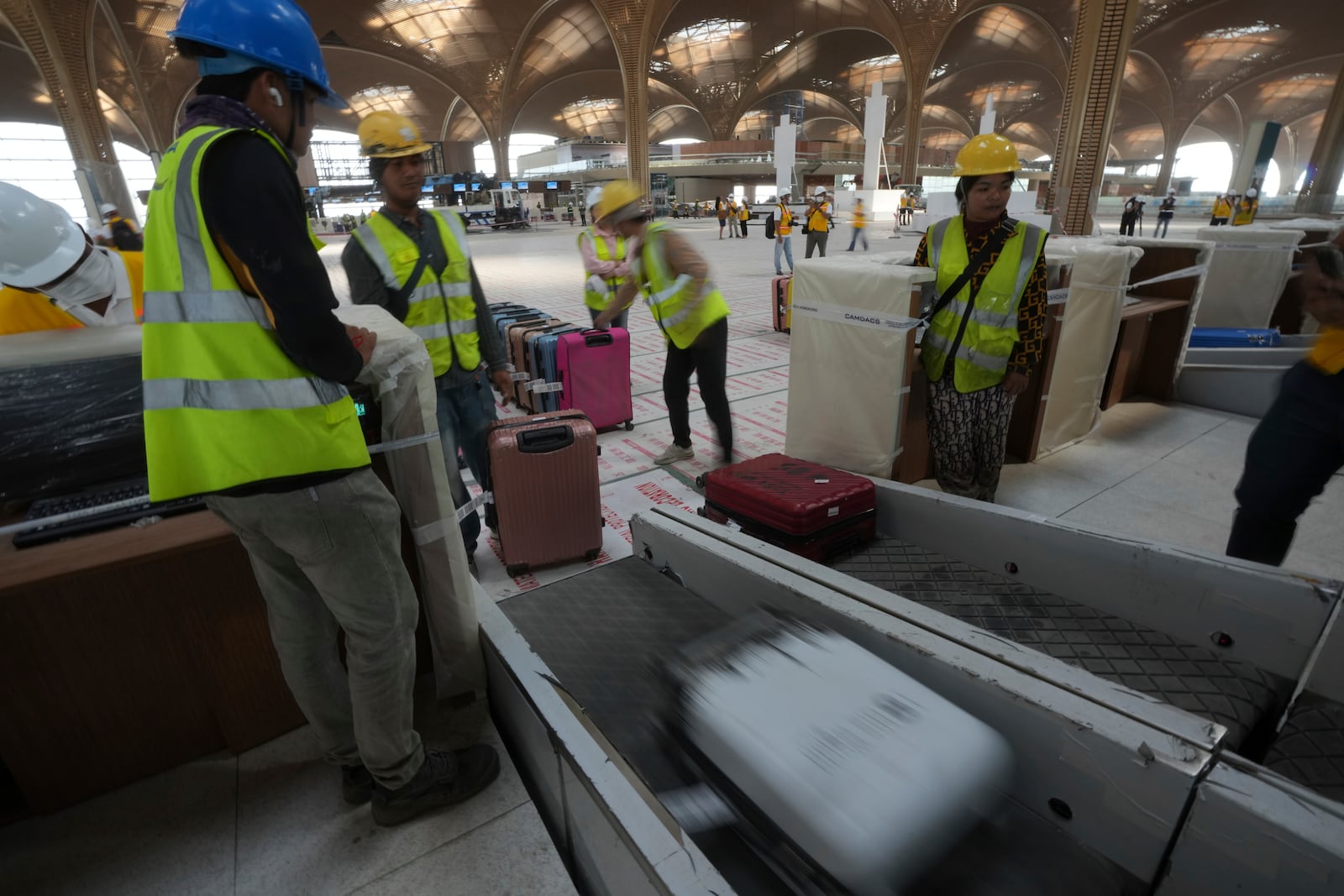 Airport staff members test the luggage machine inside an under construction of a new airport of Techo International Airport at the outskirts of Phnom Penh Cambodia, Friday, March 21, 2025. (AP Photo/Heng Sinith)