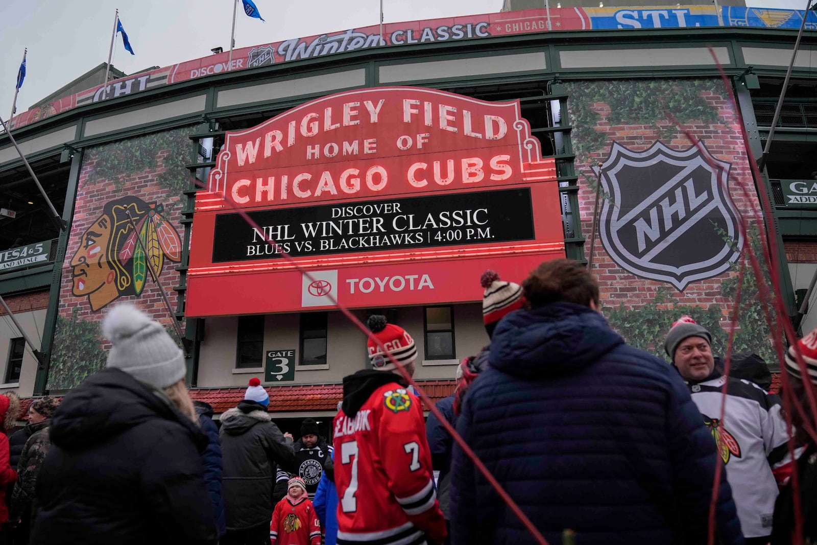 Fans hang outside of Wrigley Field before the NHL Winter Classic outdoor hockey game between the Chicago Blackhawks and St. Louis Blues, Tuesday, Dec. 31, 2024, in Chicago. (AP Photo/Erin Hooley)