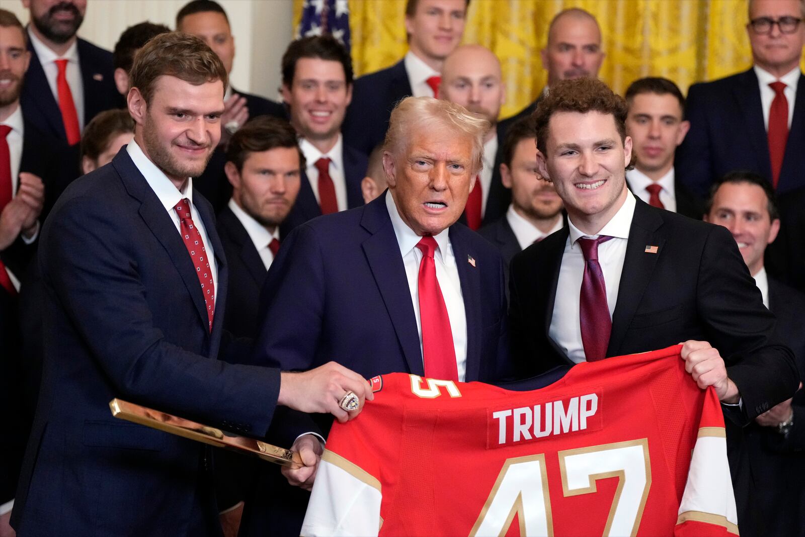 President Donald Trump poses for a photo with Aleksander Barkov, left, and Matthew Tkachuk with a jersey and a hockey stick during a ceremony with the Florida Panthers NHL hockey team to celebrate their 2024 Stanley Cup win, in the East Room of the White House, Monday, Feb. 3, 2025, in Washington. (AP Photo/Alex Brandon)