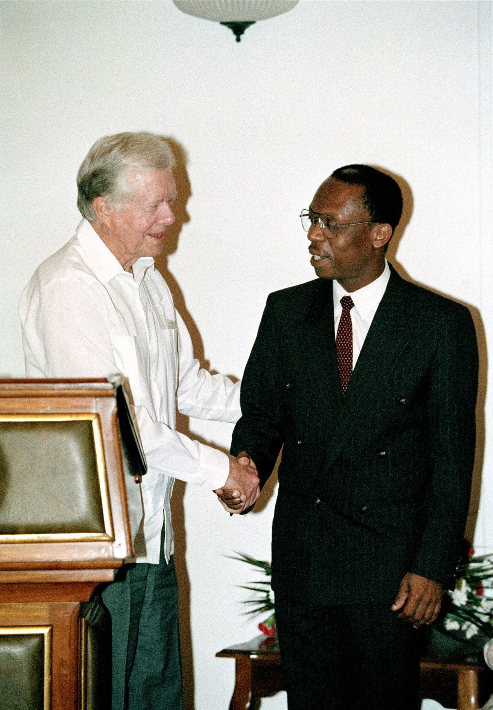 FILE - Former President Jimmy Carter shakes hands with Haitian President Jean-Bertrand Aristide at the Presidential Palace in Port-au-Prince in Haiti, Feb. 23, 1995. (AP Photo/Andrew Innerarity, File)