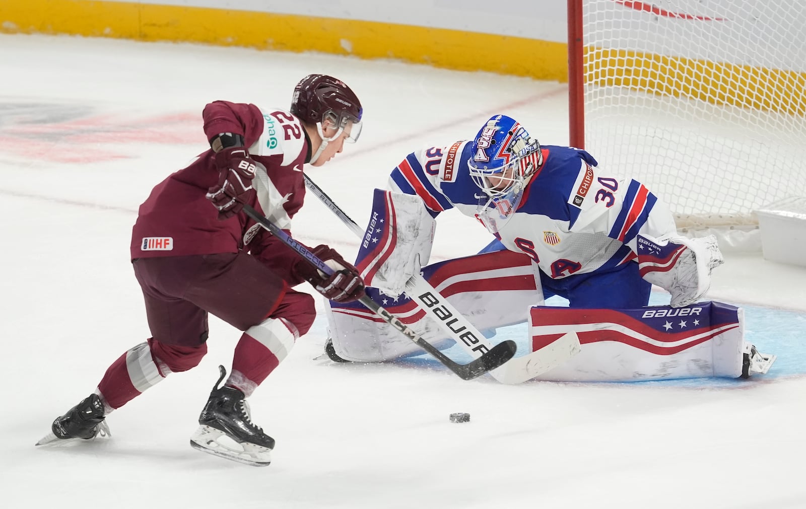 Latvia forward Valdis Dommers (22) tries to score on United States goaltender Hampton Slukynsky (30) during the second period of a IIHF World Junior Hockey Championship tournament game, Saturday, Dec.28, 2024 in Ottawa, Ontario. (Adrian Wyld/The Canadian Press via AP)