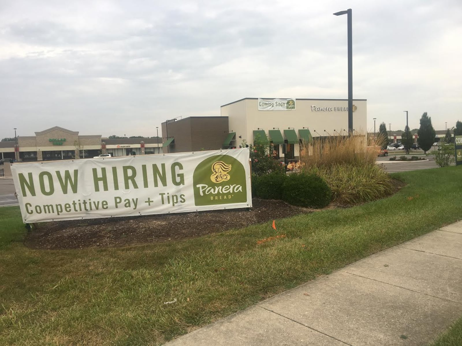 A "Coming Soon" sign hangs from a Panera Bread at the coroner of Lyons Road and Drexel Park Lane near Sam's Club.