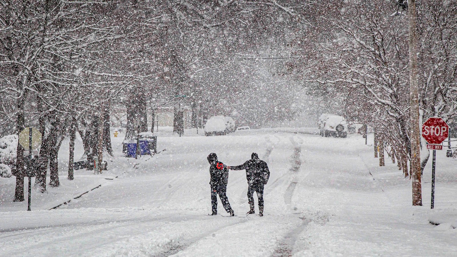 A person hangs onto another while crossing a snow-covered East Tuscaloosa Street, Friday, Jan. 10, 2025, in Florence, Ala. (Dan Busey/The TimesDaily via AP)