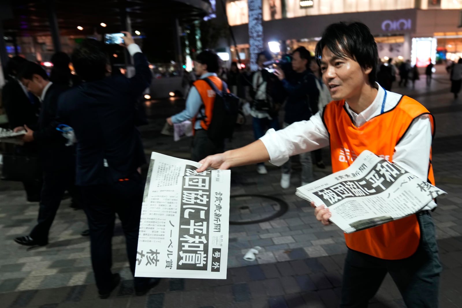 A worker of the Yomiuri Shimbun newspaper hands out copies of an extra version to passersby in Tokyo, Friday, Oct. 11, 2024, after Nihon Hidankyo, or the Japan Confederation of A- and H-Bomb Sufferers Organizations, won the Nobel Peace Prize. (AP Photo/Shuji Kajiyama)