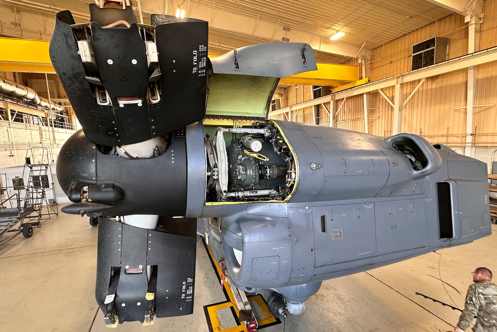 A service member walks under the Osprey nacelle, which houses both the Osprey's engine and transmission system and bends upward like an elbow during vertical flight at Cannon Air Force Base, N.M., Oct. 8, 2024. The open panel shows the proprotor gearbox, which serves as the transmission and has been a factor in multiple crashes after parts wore down and broke apart in flight. (AP Photo/Tara Copp)