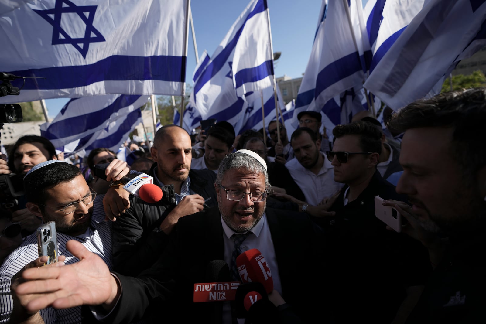 FILE - Israeli lawmaker Itamar Ben-Gvir, center, speaks to the media surrounded by right wing activists as they gather for a march in Jerusalem, April 20, 2022. (AP Photo/Ariel Schalit, File)