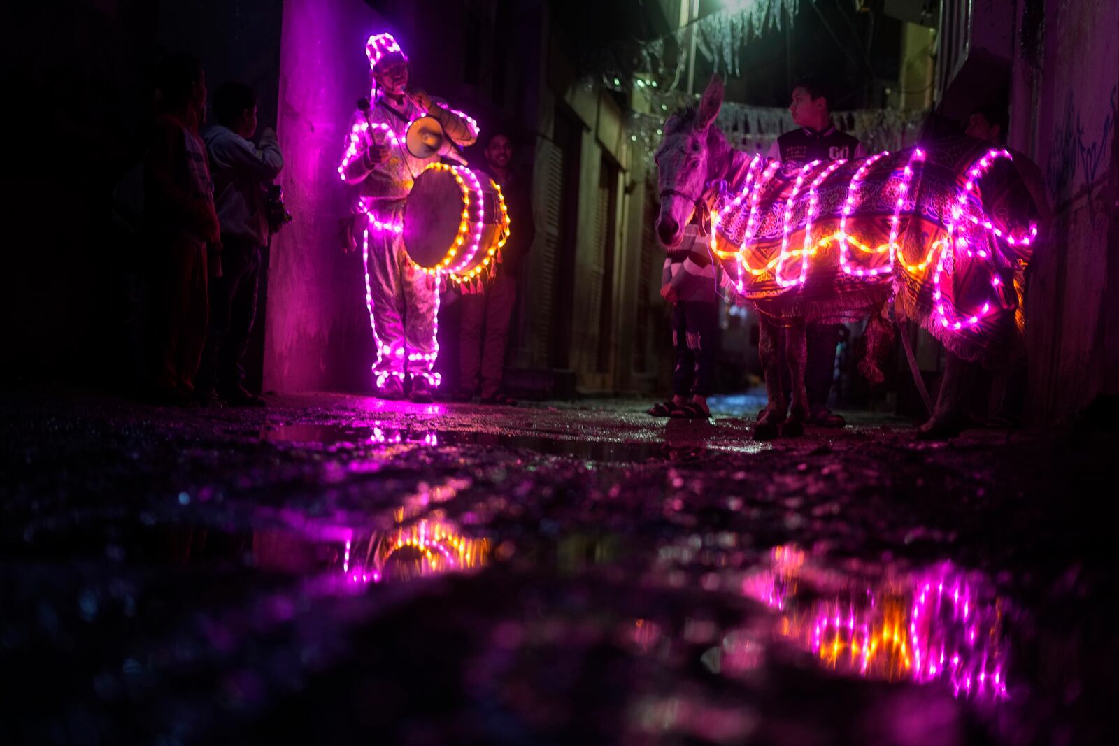 FILE - Mohammed El-Dahshan, 38-year-old "mesaharati," or dawn caller, accompanies his donkey wrapped with colored led lights to wake Muslims up for a meal before sunrise, during the Islamic holy month of Ramadan, in the Delta city of Dikernis, Egypt, about 93 miles (150 kilometers) north of Cairo, early Wednesday, April 12, 2023. Each night, El-Dahshan, sets out after midnight with his donkey banging his drum, chanting traditional religious phrases and calling out on residents by name to wake them in time for the vital pre-dawn meal known as "suhoor". (AP Photo/Amr Nabil, File)