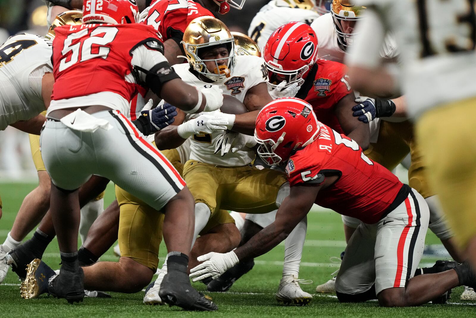 Notre Dame running back Jadarian Price, center, is tackled by Georgia linebacker Raylen Wilson (5) during the second half in the quarterfinals of a College Football Playoff, Thursday, Jan. 2, 2025, in New Orleans. (AP Photo/Gerald Herbert)