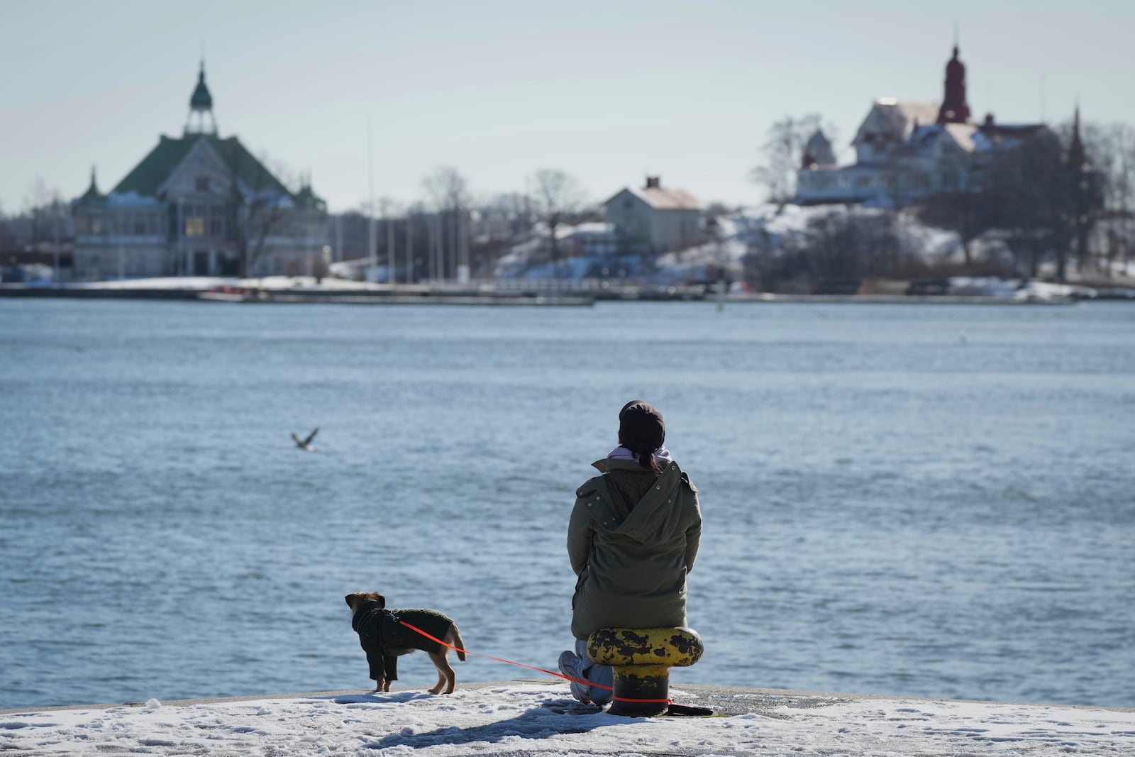 A woman enjoys a sunny and frosty day on the embankment of the South Harbour in Helsinki, Finland, Saturday, March 15, 2025. (AP Photo/Sergei Grits)