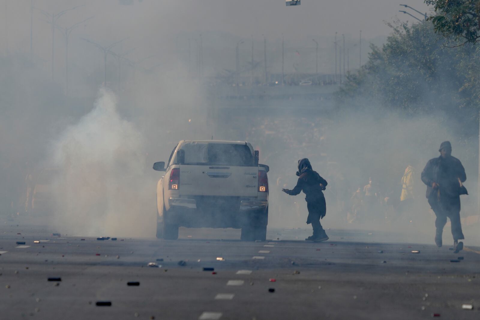 Supporters of imprisoned former Premier Imran Khan's Pakistan Tehreek-e-Insaf party run for cover as police fire tear gas shells to disperse them during clashes in Islamabad, Pakistan, Tuesday, Nov. 26, 2024. (AP Photo/Anjum Naveed)