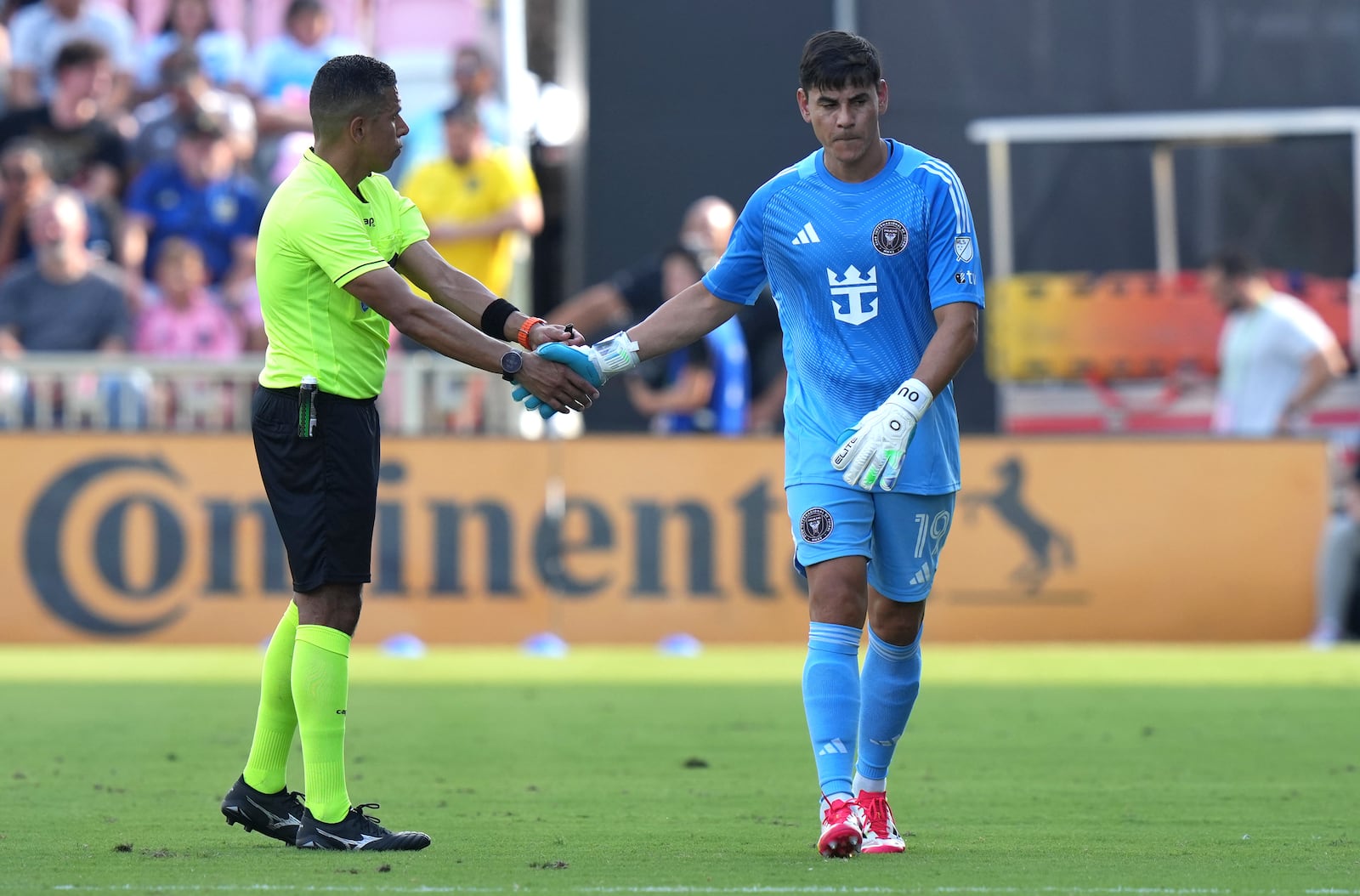 Inter Miami goalkeeper Oscar Ustari, right, shakes hands with an official as he walks off the field after being given a red card during the first half of an MLS soccer match against Charlotte FC, Sunday, March 9, 2025, in Fort Lauderdale, Fla. (AP Photo/Lynne Sladky)