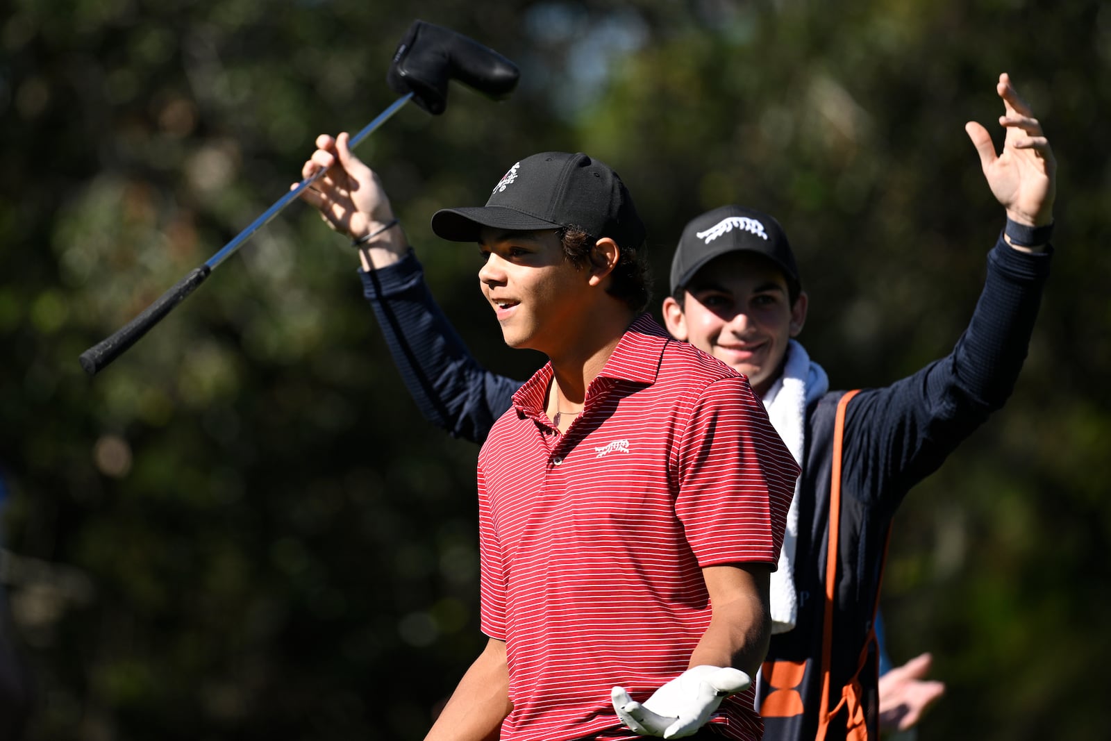 Charlie Woods, front, and his caddie Luke Wise react after his hole-in-one on the fourth hole during the final round of the PNC Championship golf tournament, Sunday, Dec. 22, 2024, in Orlando, Fla. (AP Photo/Phelan M. Ebenhack)