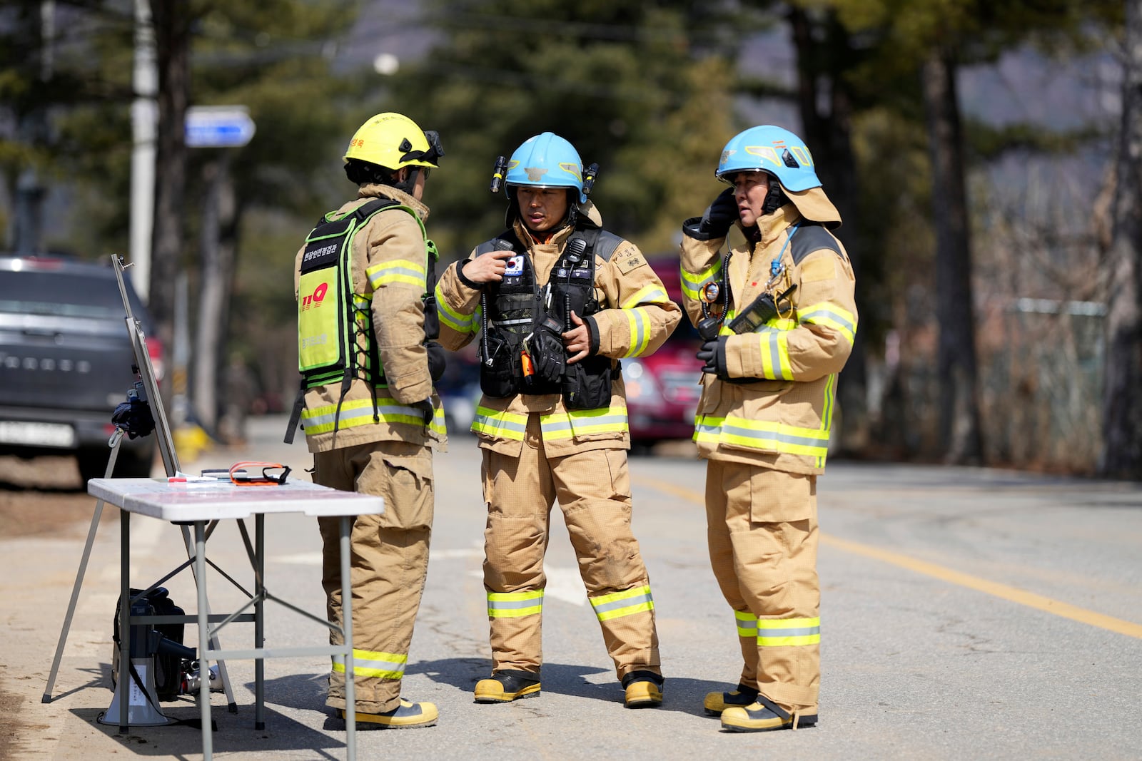 Firefighters talk each others near the scene where a South Korean fighter jet accidentally dropped bombs on a civilian area during training, in Pocheon, South Korea, Thursday, March 6, 2025. (AP Photo/Lee Jin-man)