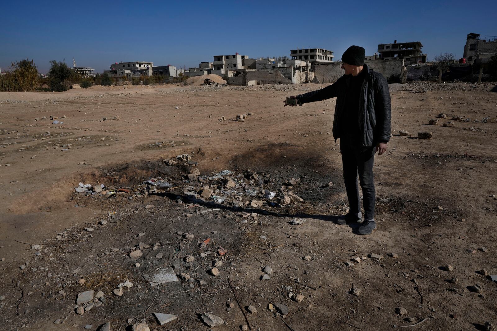 Hassan Arbeeni, 42, shows a crater where a surface-to-surface missile loaded with sarin struck, during a 2013 chemical weapons attack that was blamed on then President Bashar Assad's forces, in Zamalka neighbourhood, on the outskirts of Damascus, Syria, Wednesday, Dec. 25, 2024. (AP Photo/Hussein Malla)