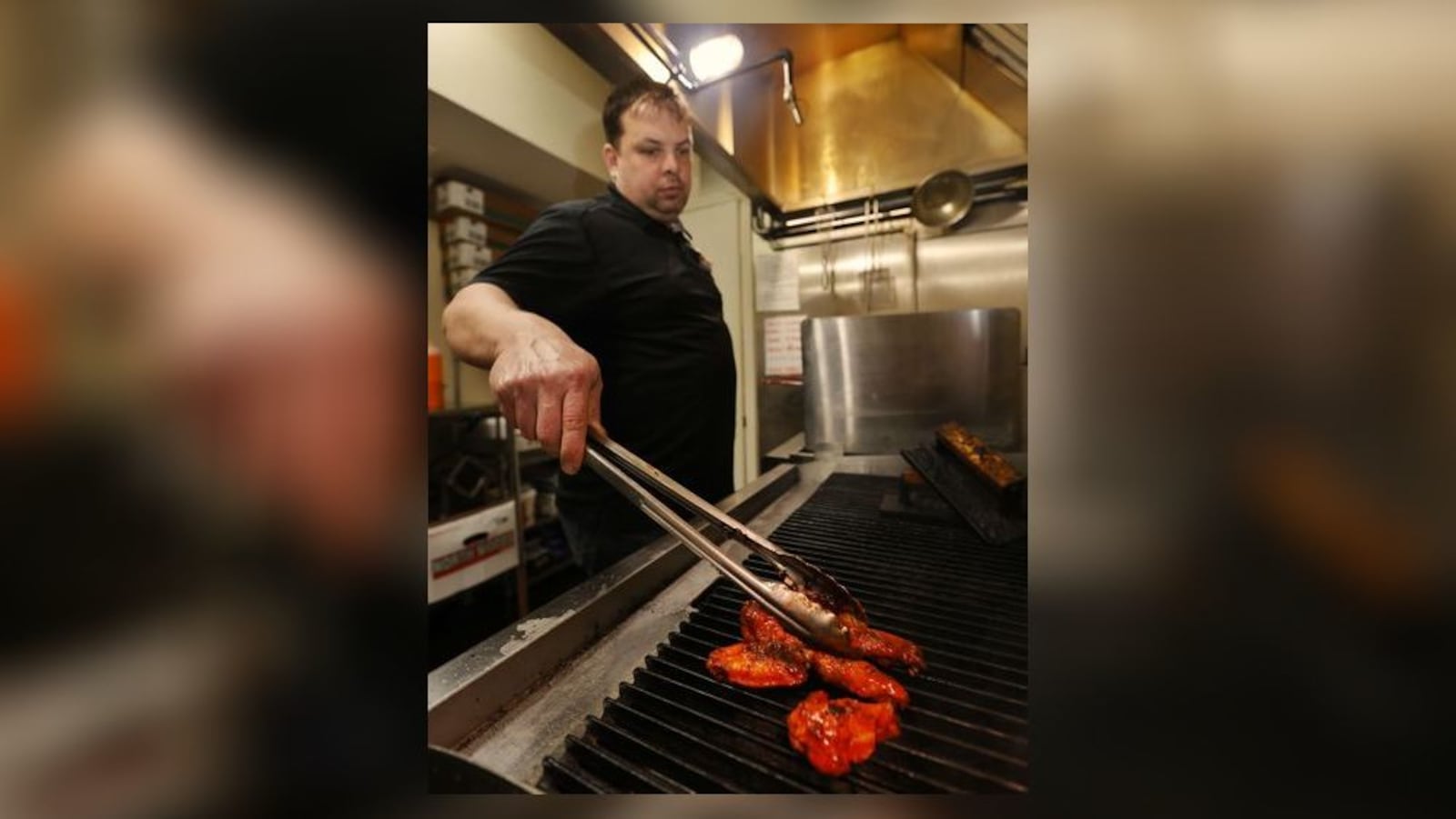 Brent Dalton cooks an order of chicken wings on the grill at Brent's Smokin' Butts on Central Avenue in Middletown. His business normally is closed on Sundays but it's taking pre-orders that can be picked up on Sunday for the Super Bowl. NICK GRAHAM/STAFF