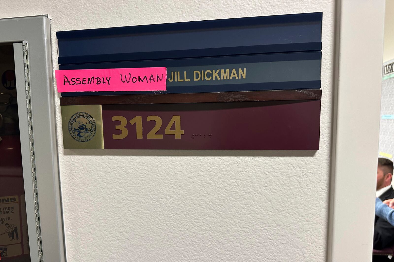 This photo provided by Jill Dickman, a GOP lawmaker in the Nevada State Assembly, shows bright pink tape labeled "ASSEMBLY WOMAN" which she placed over the sign in front of her office on Thursday, Feb. 6, 2025, after discovering it read "ASSEMBLYMEMBER" at the start of the 2025 session in Carson City, Nev. (Jill Dickman via AP)