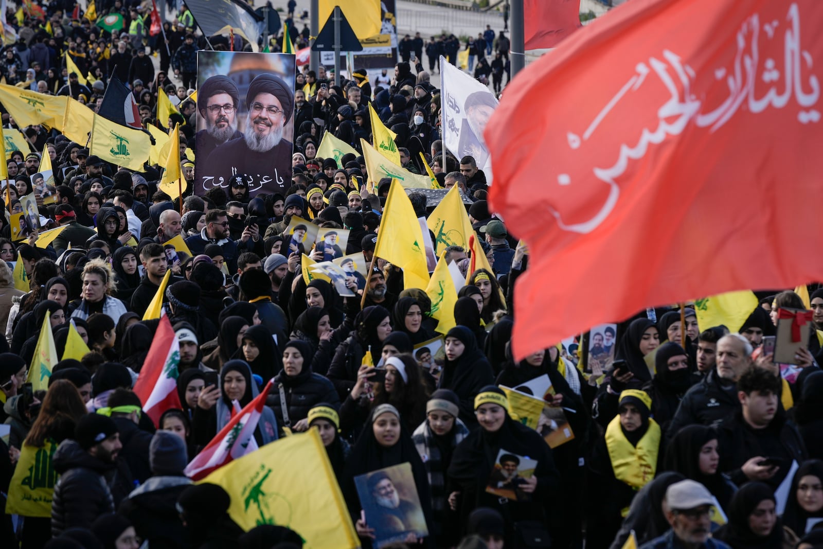 Mourners hold pictures of Hezbollah's former leader Hassan Nasrallah and his cousin and successor Hashem Safieddine as they gather along a highway to attend their funeral procession in Beirut, Lebanon, Sunday Feb. 23, 2025. (AP Photo/Bilal Hussein)