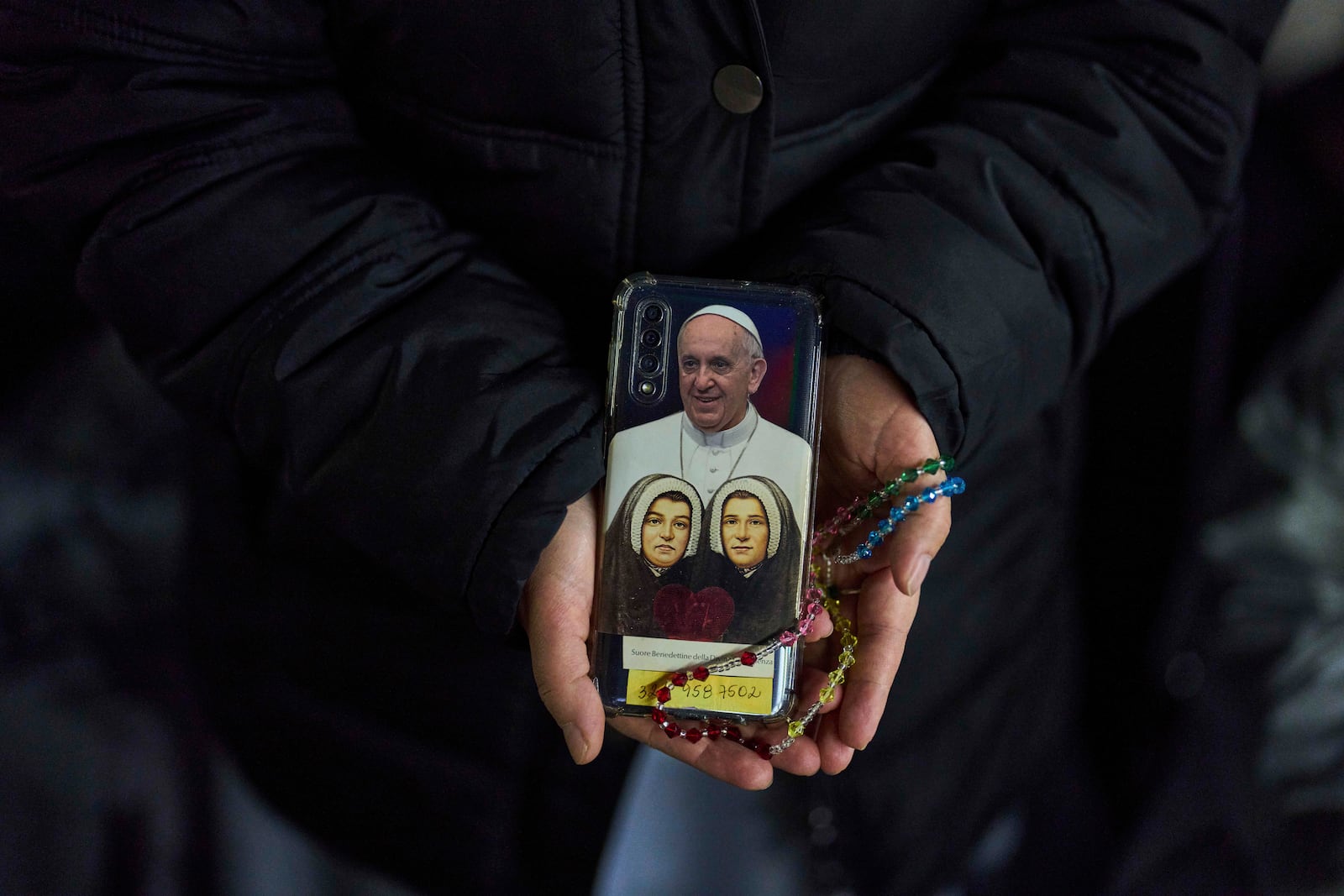 A Catholic nun shows the back cover of her mobile phone with a photograph of Pope Francis as she attends a nightly rosary prayer service for Pope Francis in St. Peter's Square at the Vatican, Thursday, March 6, 2025. (AP Photo/Francisco Seco)