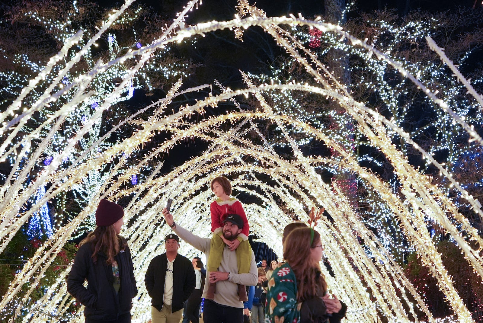 A family walks through a light display at the Lights of Joy display Monday, Dec. 16, 2024, in Kennesaw, Ga. (AP Photo/Brynn Anderson)