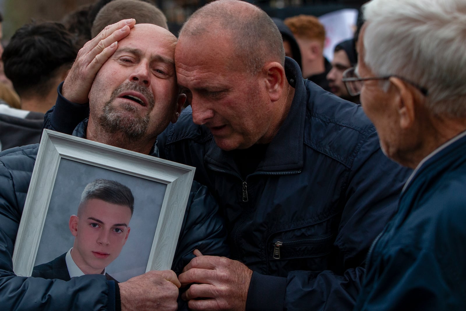 Dragi Stojanov, left, cries holding a photograph of his son Tomche Stojanov, one of the victims of a massive nightclub fire, during a vigil joined by hundreds in the town of Kocani, North Macedonia, Monday, March 17, 2025. (AP Photo/Visar Kryeziu)